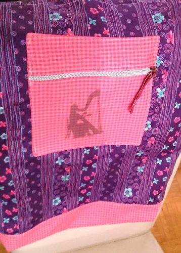 Selbstgenähter Lila Beutel als Harfentasche. Detailansicht der Aufgesetzten Tasche auf dem Beutel, die das Bild der Harfinistin trägt.