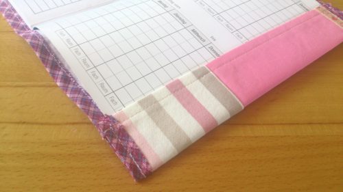 Hefteinband selbstgenäht: Rosa Einband aufgeklappt mit eingelegtem Hausaufgabenheft. Detailansicht