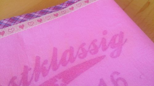 Hefteinband selbstgenäht: Rosa Einband Detailansicht der Bänderverzierungen und des Fototransfer Schriftzuges