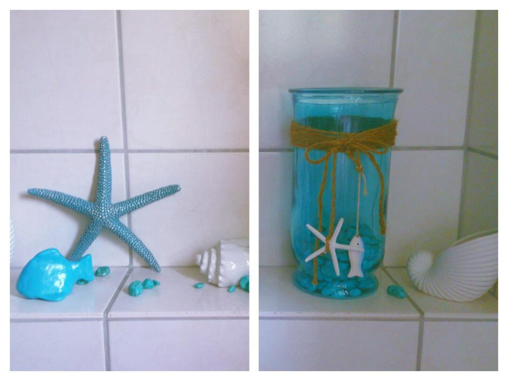 Selbstgebastelter Fisch aus Fimo in karibischem ozeanblau als Deko zwischen Muscheln und Seestern. Hellblaues Glas mit Steinen am Boden, dekoriert mit Fisch und Seestern.