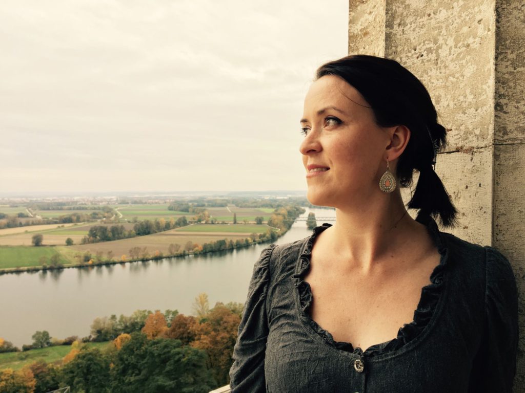Kleid aus grauem crashed Jersey langärmelig, Portraitaufnahme, im Hintergrund sieht man die Donau und Regensburg 