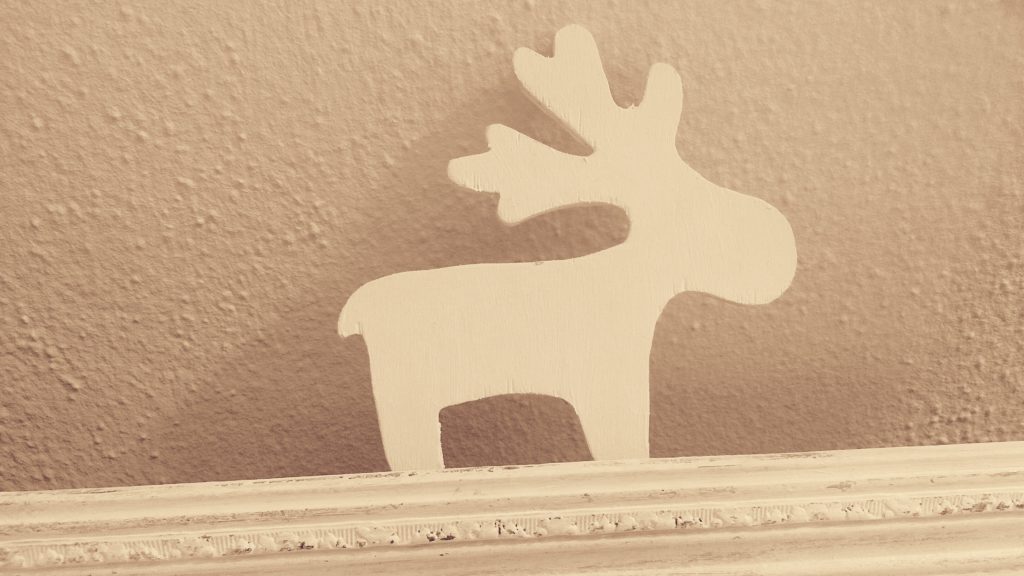 der kleine Holzelch im Detail, der an der Wand lehnt im verschnörkelten Bilderramen