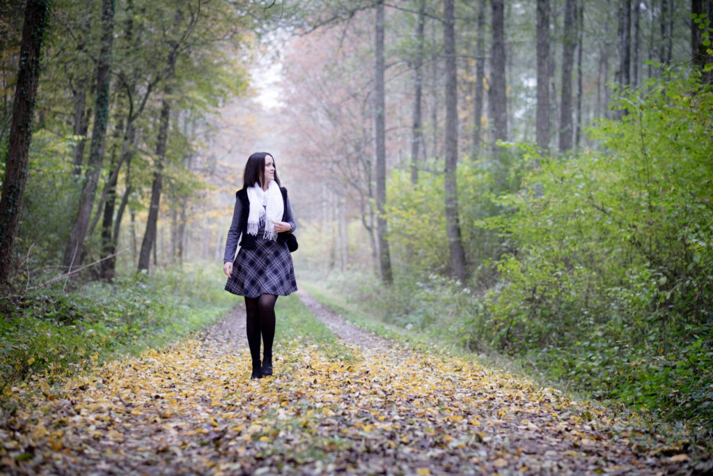 Spaziergang im Wald, nebliger Waldweg. Gesamtoutfit mit Rock, Shirt, Weste und Schal