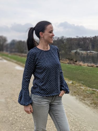 Selbe Perspektive: der Pullover von vorne. Ein Arm ist ausgestreckt, sodass man den puffigen Fall des Ärmels gut sieht.