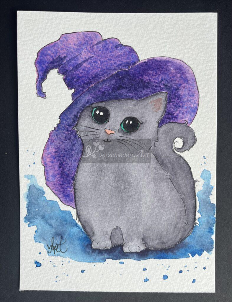 Aquarellbild auf weißem Papiert: Graues Kätzchen mit großen grünen Augen hält den Kopf leicht geneigt weil es einen großen lila Hexenhut auf dem Kopf trägt.