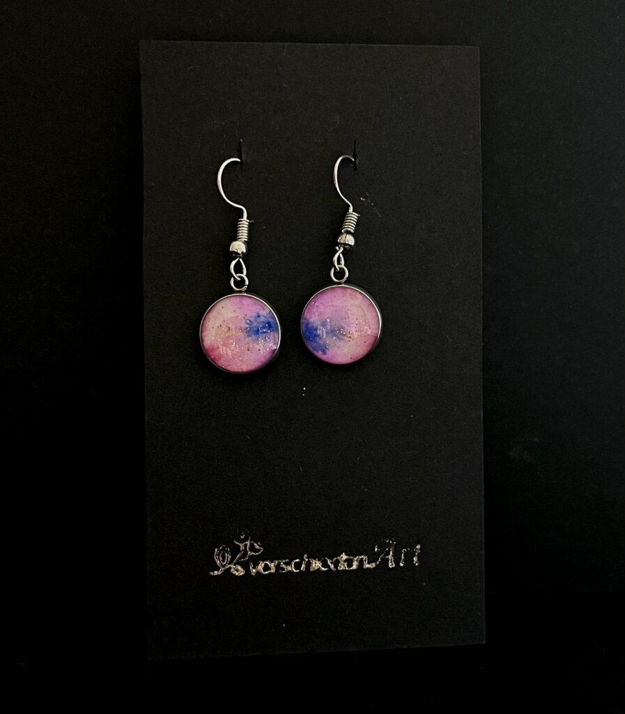 silberne Ohrringe mit rundem Anhänger. Motiv: abstrakt verschwommene Farben: Rosa- und Blautöne mit schwebenden goldenen Glitzerpartikeln